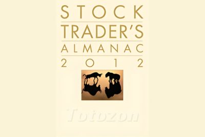 A financial trader analyzing charts and data from the Stock Trader's Almanac.