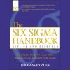 A professional reading the Six Sigma Handbook by Thomas Pyzdek, surrounded by charts and graphs