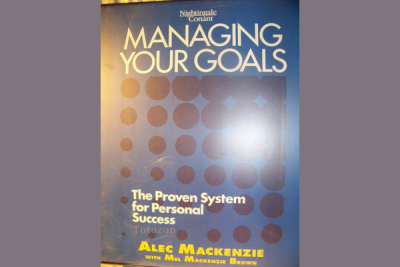 Person writing goals in a journal with Alec MacKenzie's techniques